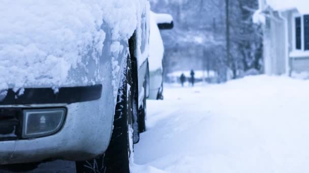 Grijze auto onder de sneeuw aan de kant van de weg op een koude ochtend. Zware sneeuwval op straat — Stockvideo