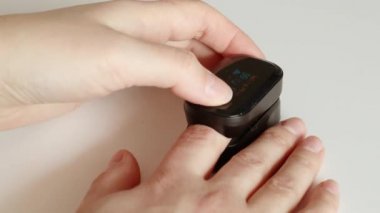 Kadın, evinde nabız oksimetresiyle kan oksijeni seviyesini ölçüyor. Koronavirüs salgını sırasında evdeki sağlığı korumak için modern teknolojiler.