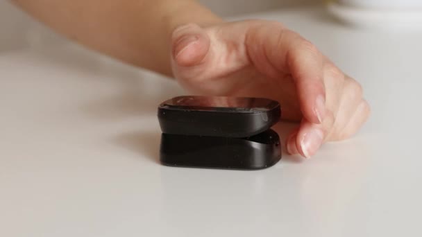 Close-up van een vrouw hand meten bloed zuurstof verzadiging niveau met een pulsoximeter thuis. Moderne technologieën ter bescherming van de gezondheid thuis tijdens de coronaviruspandemie. — Stockvideo