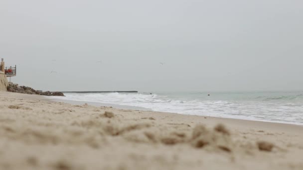 Playa de invierno con agua salpicada de olas. La ola del mar se estrella contra la playa de piedra. Nublado mañana. Mar con olas tormentosas rodando en día nublado frío invierno. — Vídeos de Stock