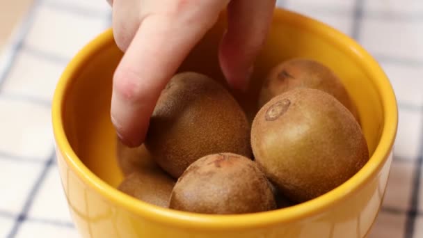 Las manos femeninas tomando kiwi de placa amarilla en la mesa de la cocina — Vídeos de Stock