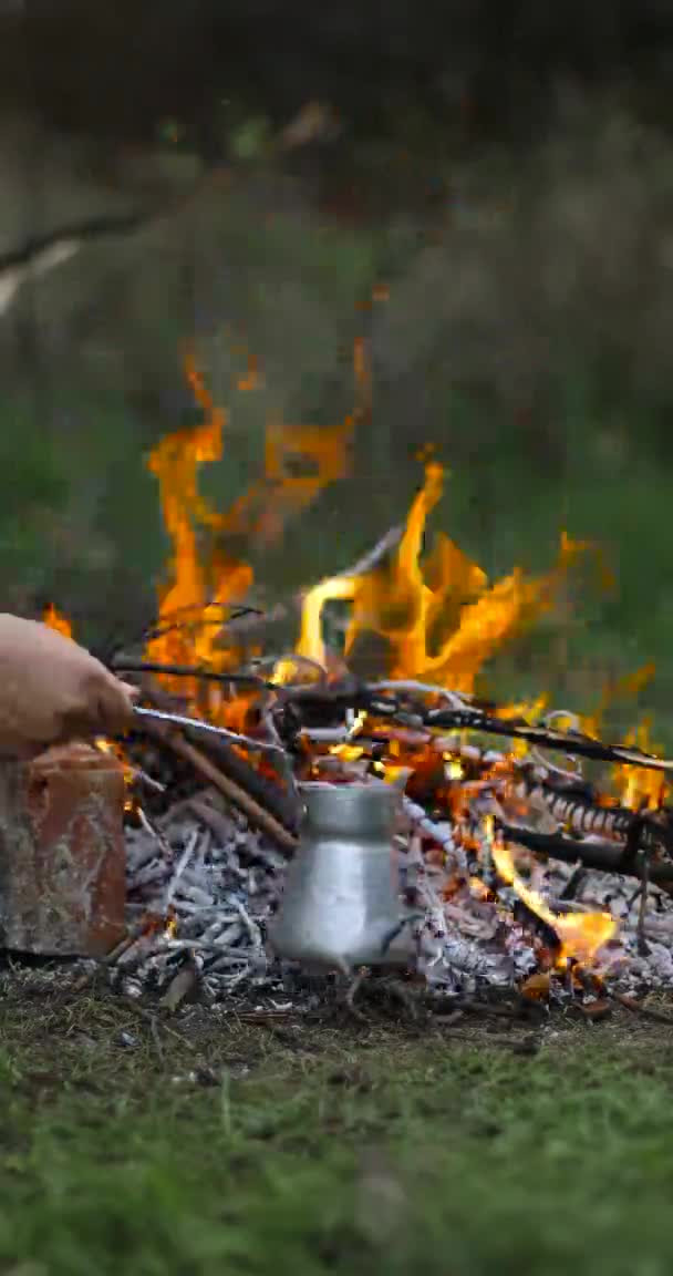 Haciendo natillas de café en una cafetera sobre fuego. Fuego en el bosque de verano. Concepto de viajes y vacaciones. — Vídeos de Stock