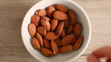 Erkek elinin mutfaktaki beyaz kaseden fındık alışının üst görüntüsü.