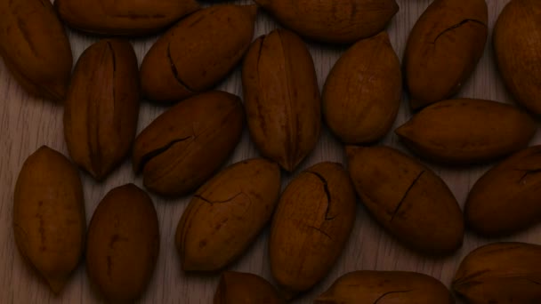 Pecanovo pozadí. Pekan ořechy v tvrdé skořápce s prasklinami na stole. Koncept potravin. — Stock video
