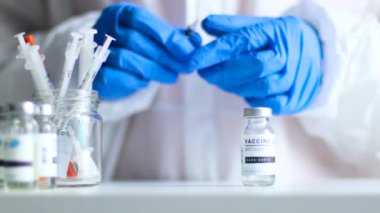 Kadın doktor bir klinik ve laboratuvarda aşıyla şırınga tutuyor.