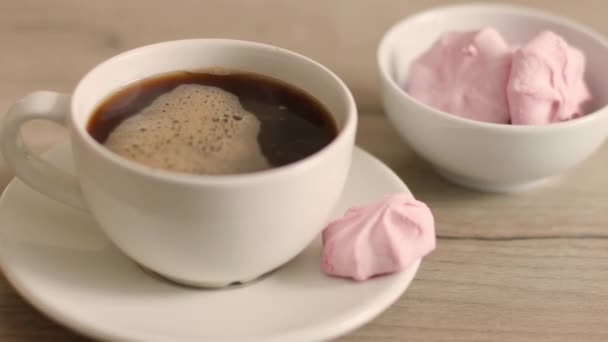 Taza de café negro con postres de malvavisco en una mesa de madera en la cafetería — Vídeo de stock