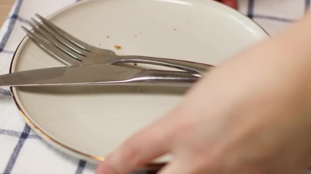 Tomma smutsiga tallrik med kniv och gaffel på bordet, kvinnliga händer tar smutsiga rätter — Stockvideo