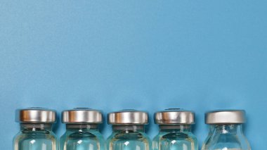 Coronavirus covid-19 deneysel aşı şişeleri laboratuarında kopyalanmış mavi bir plaka üzerinde