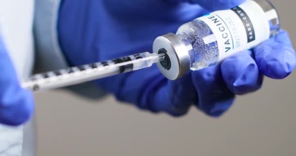 Ученый или врач в резиновых перчатках держит новую вакцину и шприц BNT162b2 для инъекции добровольцев против коронавируса Сарс-Ков-2, коронавируса или ковида-19. Разработка и исследование нового — стоковое видео