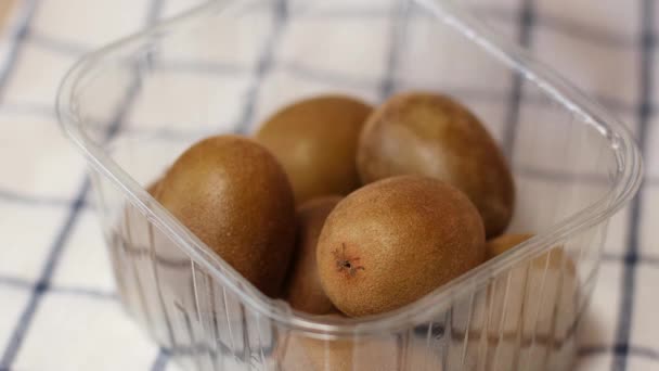 Mão leva kiwi da cesta na mesa da cozinha. — Vídeo de Stock