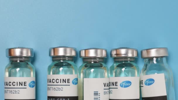 Ukrajina - leden, 11, 2021: Vakcínové lahvičky nebo koronavirové vakcinační lahvičky na modrém pozadí. Očkování, injekce, klinická studie — Stock video