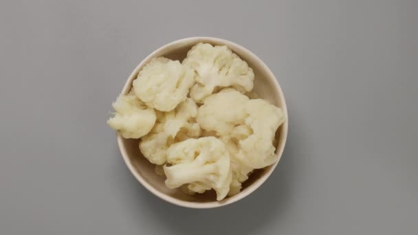 Boiled hot cauliflower in bowl on gray background — Stock Video