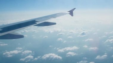 Mavi gökyüzünde bulutların üzerinde uçan uçak kanadının pencere görüntüsü