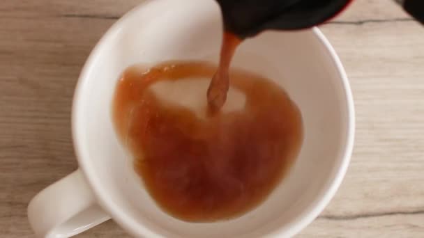 Versare il caffè in una tazza bianca usando una pentola turca sul tavolo di legno. — Video Stock