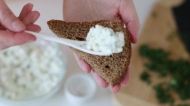 Bir parça ekmeğe krem peynir süren kişi. Tohumlu mayasız çavdar ekmeği.