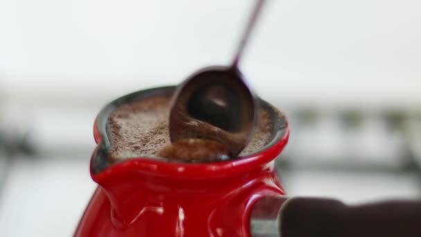 Preparare il caffè mattutino nella tradizionale caffettiera turca Le mani di Man mescolano una bevanda al caffè con un cucchiaio. Caffettiera sul piatto di cottura. — Video Stock