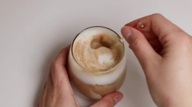 Kadının el yapımı, cam kaşıkla kahve karıştırma görüntüsü.