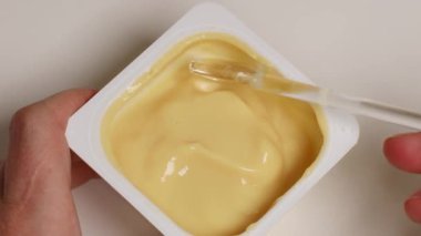 Beyaz masada kaşıkla vanilyalı mus yiyen bir kadın.