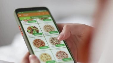 Akıllı telefon uygulaması kullanarak internetten yemek sipariş etmek. İnternetten pizza siparişi veriyor, kanepede uzanıyor yemek dağıtıyor..