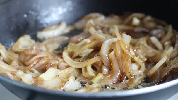 Жареный лук в масле в сковороде на домашней кухне — стоковое видео