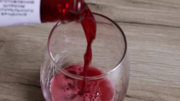 Ρίχνει κόκκινο ποτό σε ένα ποτήρι από κοντά. Ποτό, έννοια φρούτα. — Αρχείο Βίντεο