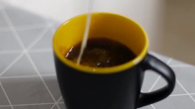 Arka planda bir fincanda Espresso kahve. Sabah kahvesine krema dökülüyor..