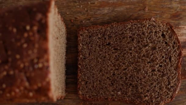 Närbild av människan ta bit bröd. Hand tar färsk skiva skivat bröd på träskiva. Jästfritt rågbröd med frön — Stockvideo