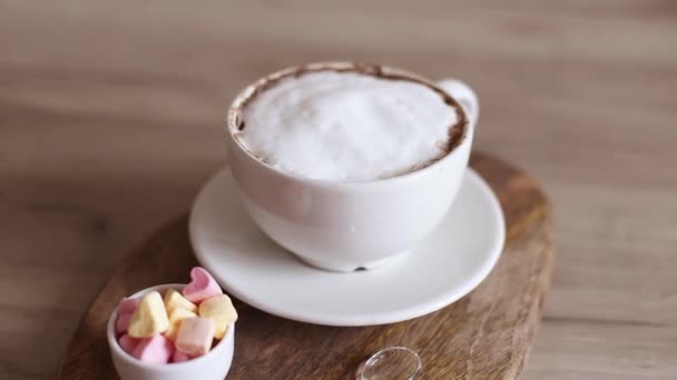 Cappuccino káva v keramickém šálku se vzduchem láska marshmallow cukroví na dřevěné desce. Chutná snídaně, domácí výroba kávy. — Stock video