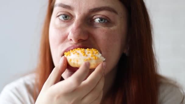 Blanke vrouw die een stuk van de smaak donut eet met mango vulling, genieten. Hongerige vrouw, close up — Stockvideo