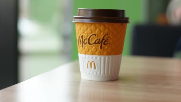 Одесса, Украина, 10 марта 2021 года: Бумажная чашка кофе с логотипом Макдональда на столе возле окна ресторана Макдональд. — стоковое видео
