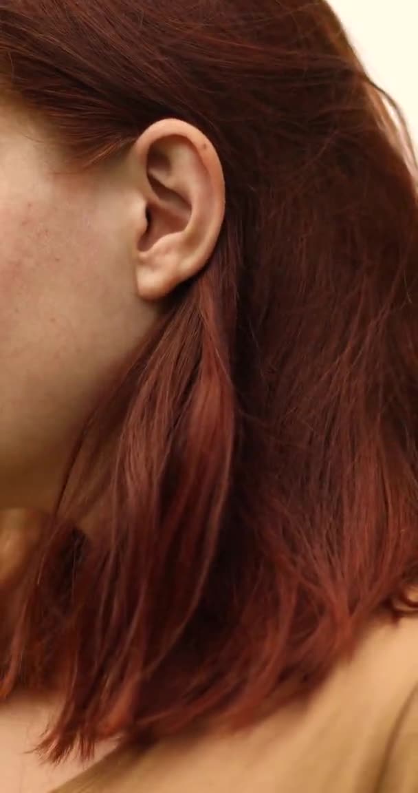Закрытие женщины, использующей красный беспроводной наушник вручную, чтобы вставить в ухо и управлять — стоковое видео