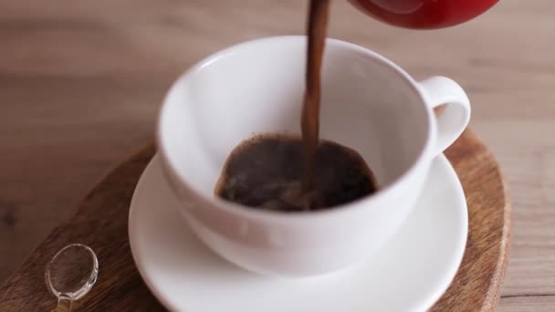 Mão feminina derramando café expresso em xícara de cerâmica na cozinha. Jezve café usando cafeteira turca — Vídeo de Stock