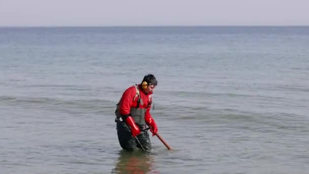 Ucraina - 27 febbraio 2021: caccia al tesoro in mare con metal detector. Uomo con metal detector alla ricerca di oggetti smarriti sotto la sabbia dell'oceano, mare. — Video Stock