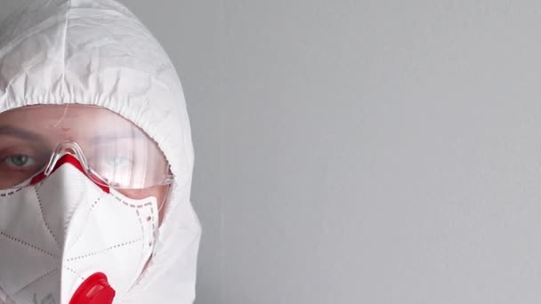Medische werker in een medisch masker, bril en beschermende witte werkkleding voor bescherming tegen coronavirus, ziekte, infectie, quarantaine, medisch masker — Stockvideo