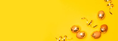 Sarı arka planda altın yumurta ve yılan. Düz konum, üst görünüm, kopyalama alanı