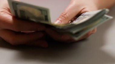 Anlaştık, iş konsepti. Kadın ya da erkek eli Amerikan para banknotlarını sayar. Kadın elleri 100 dolarlık banknotları tutuyor..