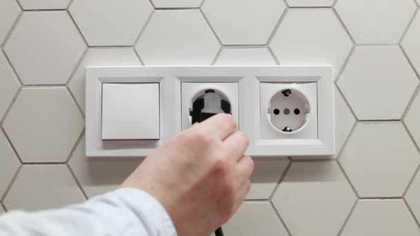 사람 이손으로 흰 벽에 검은 전기 콘센트에 플러그를 꽂는다. 전기 에너지를 절약하는 지구의 시간 — 비디오