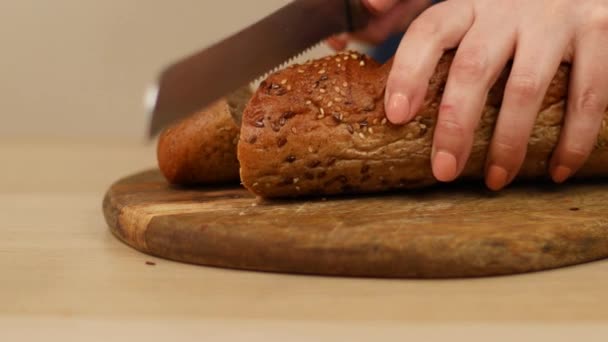 Kadın çavdar ekmeğini tohumla ve ekmek bıçağıyla ahşap mutfak tahtasına keser. Kahvaltı mı yoksa atıştırmalık mı? — Stok video