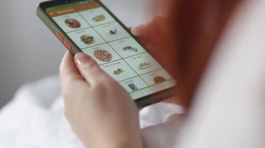 Akıllı telefon uygulaması kullanarak internetten yemek sipariş etmek. Sipariş için online dağıtım yapıyor, yatakta yatıyor. Yemek teslimatı.
