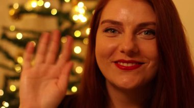 Noel arifesinden zevk alan mutlu bir kadının yakın plan portresi. Noel ağacı süslerinde poz veriyor. İçi aydınlanmış..