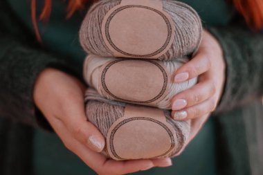 Kadın elleri, boş etiketli renkli yün alpaka iplik toplarını tutar