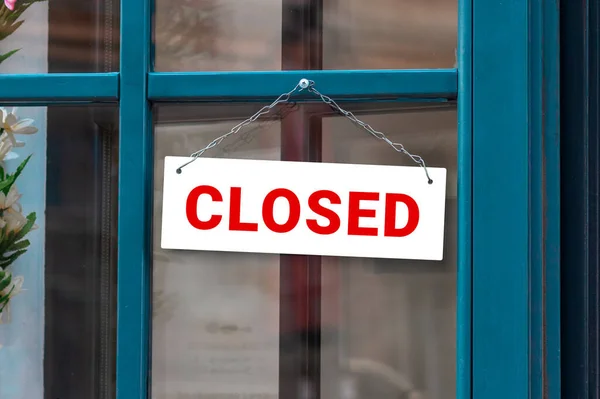 Close up on closed sign in the window of a shop with inscription Closed due to Covid-19. Coronavirus outbreak lockdown