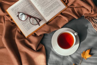 Sonbahar yapraklı sıcak çay ve yatakta kahverengi ekose üzerine açık çelenk. Rahatlık ve rahatlama kavramı,