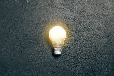 Koyu grunge arka planda parlak bir ampul yandı. Yaratıcı ilham, fikir planlama kavramı. Düz yatış, üst görünüm