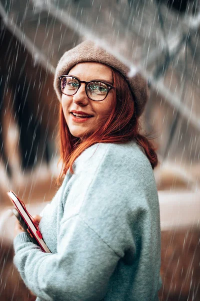 Όμορφη κοκκινομάλλα κοπέλα με γυαλιά και βιβλία για μελέτη κοίτα την κάμερα στο πάρκο — Φωτογραφία Αρχείου