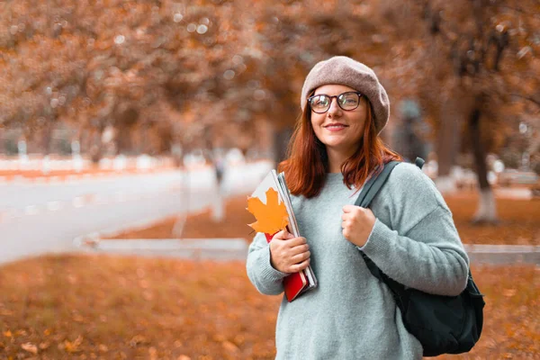 Γυναίκα φοιτήτρια περπατώντας στο πάρκο, φορώντας καθημερινά ρούχα με γυαλιά, κρατώντας σημειωματάρια και βιβλία στο πάρκο πανεπιστημιούπολη — Φωτογραφία Αρχείου
