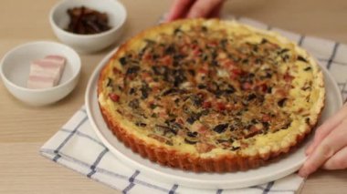 Pastırmalı, mantarlı ve soğanlı ev yapımı kiş. Kadın eli tabağa taze pişmiş turta koyar. Tavuklu tart. Tavuklu pasta.