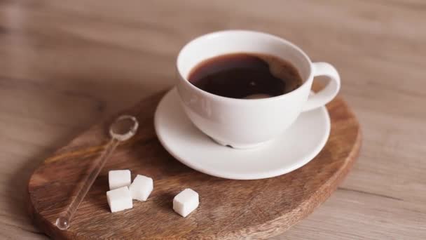 Beyaz bardakta mis kokulu americano kahvesi ve mutfakta tahta tahtada şeker küpleri. — Stok video