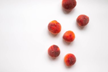 Olgun taze şeftalilerin en üst görüntüsü kaotik bir şekilde beyaz bir masada yatıyor. Çiğ yiyecek ve meyve kavramı