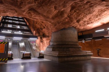 Stockholm, İsveç 7 Haziran 2019: Yeraltı metro tünel istasyonu Radhuset yürüyen merdiven ve turuncu kahverengi desenli mağara duvarları ve tavan